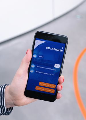 Eine Hand hält ein Smartphone auf dessen Bildschirm die App "Frag Walfred!" zu sehen ist