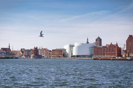 Ein weißes Gebäude zwischen Backsteinbauten am Meer