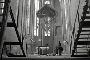 Schwarz-Weiß-Aufnahme eines hängenden Walskeletts in einer Kirchenhalle