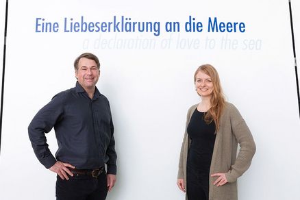 Karsten Goletz und Anke Neumeister im OZEANEUM vor dem Schriftzug „Eine Liebeserklärung an die Meere“