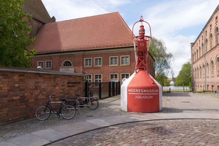 Eine rot-weiß-gestreifte Tonne, die einst als Schifffahrtszeichen diente, steht nun am Eingang des derzeit geschlossenen MEERESMUSEUMs