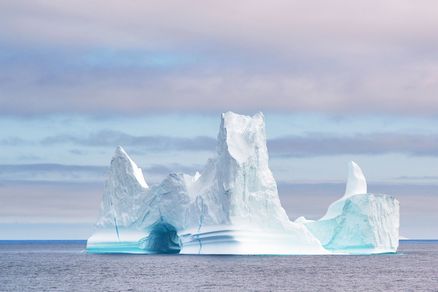 Ein Eisberg um geben von Wasser und Wolkenhimmel.