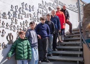 Personen stehen auf einer Treppe, im Hintergrund Pinguinkeramiken an einer Wand
