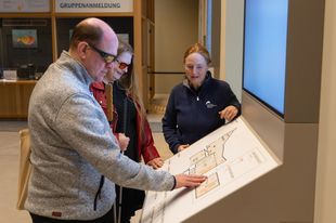 Blind people explore a tactile floor plan of the building.