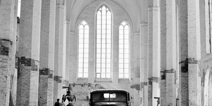 Schwarz-Weiß-Aufnahme zeigt einen historischen LKW in einem entkernten Kirchengebäude