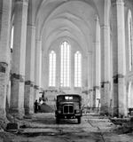 Schwarz-Weiß-Aufnahme zeigt einen historischen LKW in einem entkernten Kirchengebäude
