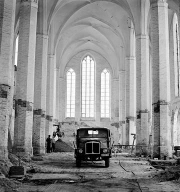 Schwarz-Weiß-Aufnahme zeigt einen historischen LKW in einem entkernten Kirchengebäude