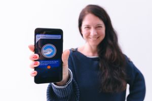 Frau hält ihr Smartphone in die Kamera