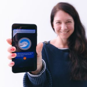 Eine Frau hält ein Smartphone mit der "Frag Walfred!" App in Richtung Kamera.