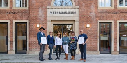 Eine Gruppe vor einem Backsteingebäude mit dem Schriftzug "MEERESMUSEUM" über der Tür