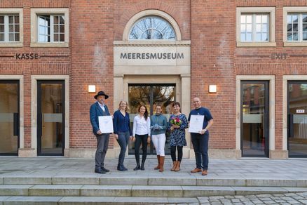 Eine Gruppe vor einem Backsteingebäude mit dem Schriftzug "MEERESMUSEUM" über der Tür