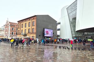 Gästeschlange im Regen vor einem weißen Gebäude