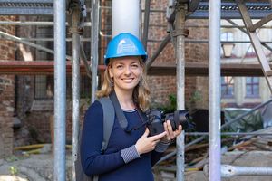 Fotografin mit Bauhelm und Kamera auf der Baustelle