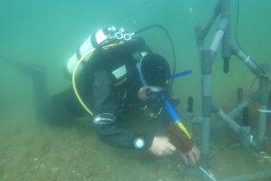 Taucher bringt unter Wasser eine technische Ausrüstung an