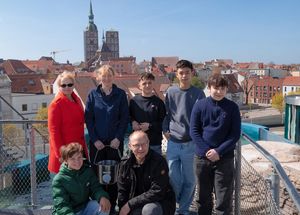 Eine Gruppe auf einer Dachterrasse, im Hintergrund Dächer und Kirchengebäude einer Stadt