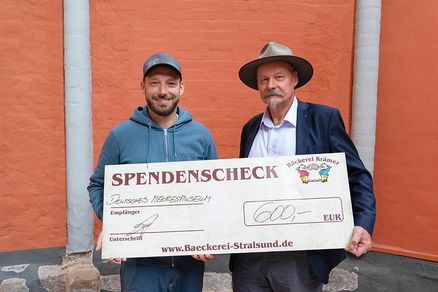 Bäcker Martin Krämer überreicht Andreas Tanschus einen Spendenscheck. (Foto: Anke Neumeister/Deutsches Meeresmuseum)