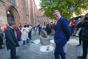 Menschen um eine Steinstatue, umgeben von Sand