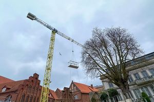 Ein Kran hebt ein Gestell hoch in die Luft