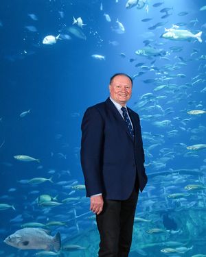 Ein Mann im Anzug steht vor einem raumhohen Aquarium