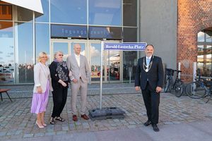 Vier Personen stehen an einem Straßenschild mit dem Titel "Harald-Lastovka-Platz"